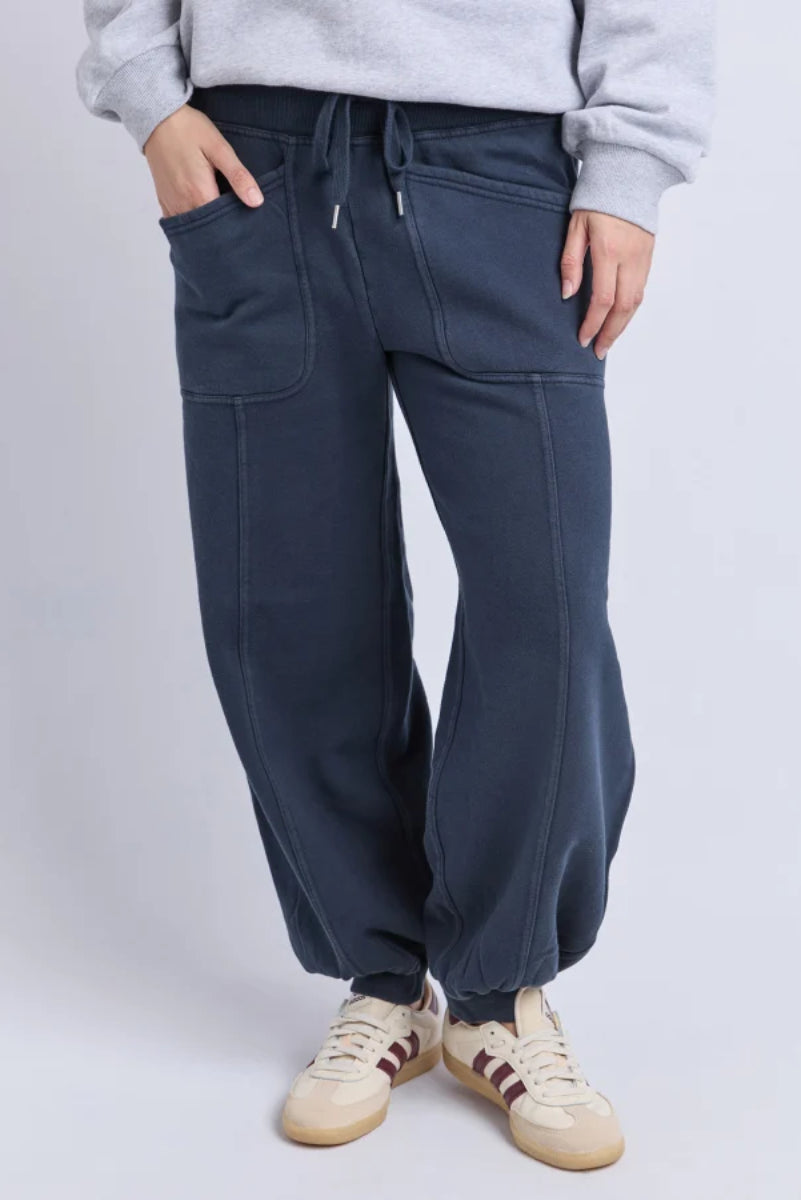 Person wearing navy blue jogger pants with a plain background