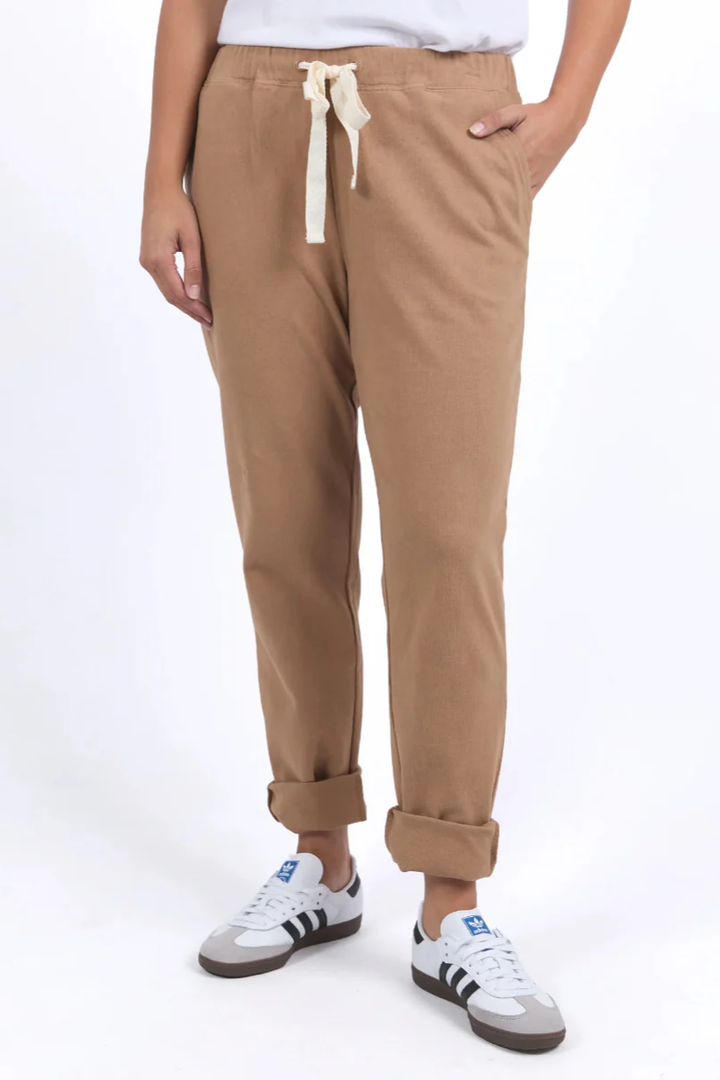 Person wearing tan jogger pants with a white background
