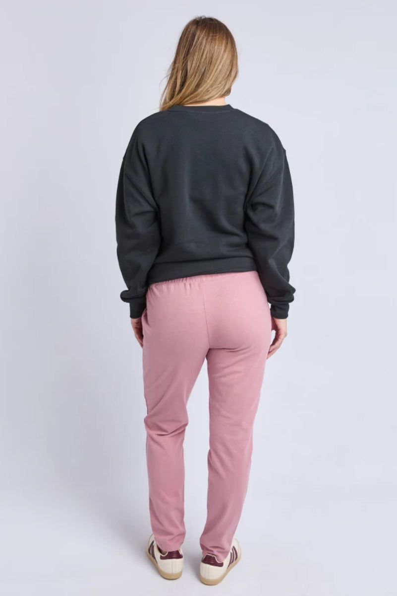 Person wearing a dark gray sweatshirt and pink pants on a white background