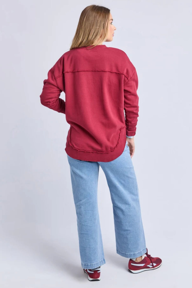 Person wearing a red sweatshirt and blue jeans on a light gray background