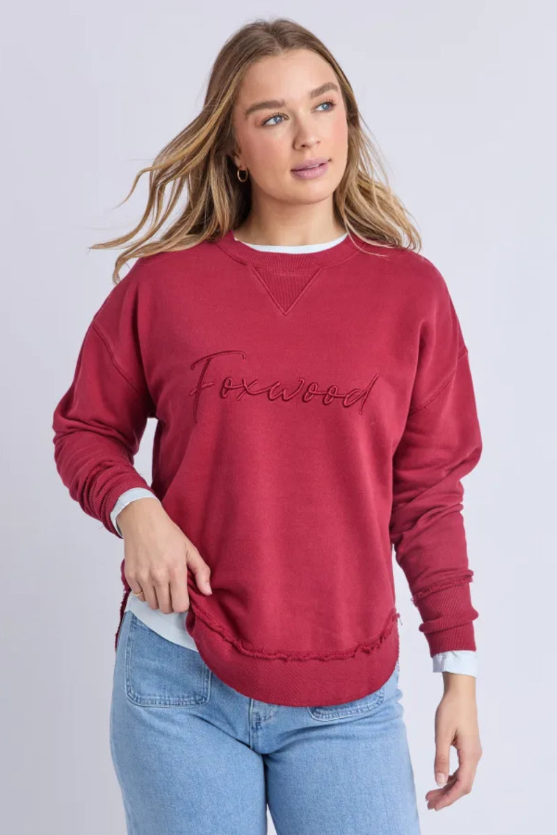 Woman wearing a red sweatshirt with 'Foxwood' text on a plain background
