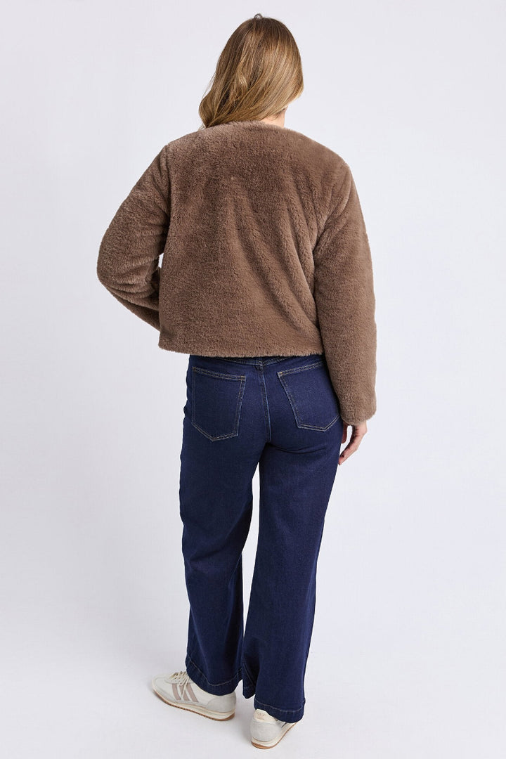 Person wearing a brown sweater and blue jeans on a white background