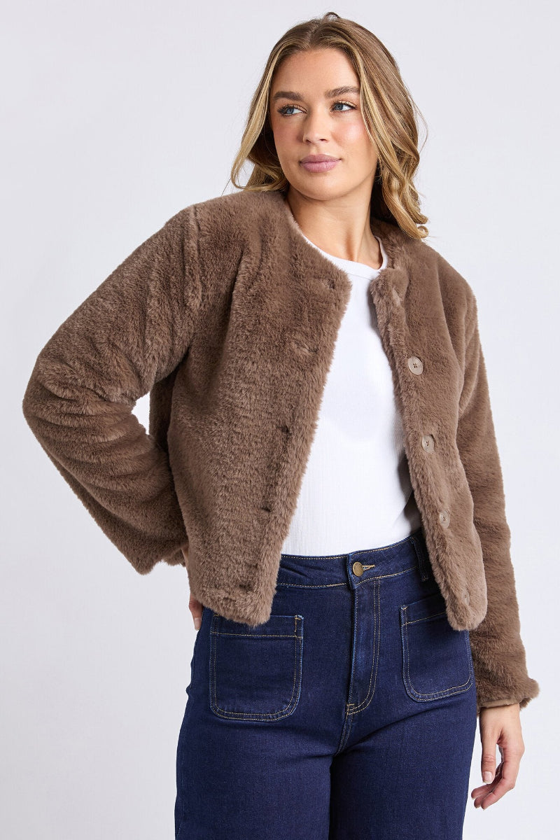 Woman wearing a brown fleece jacket and blue jeans on a white background