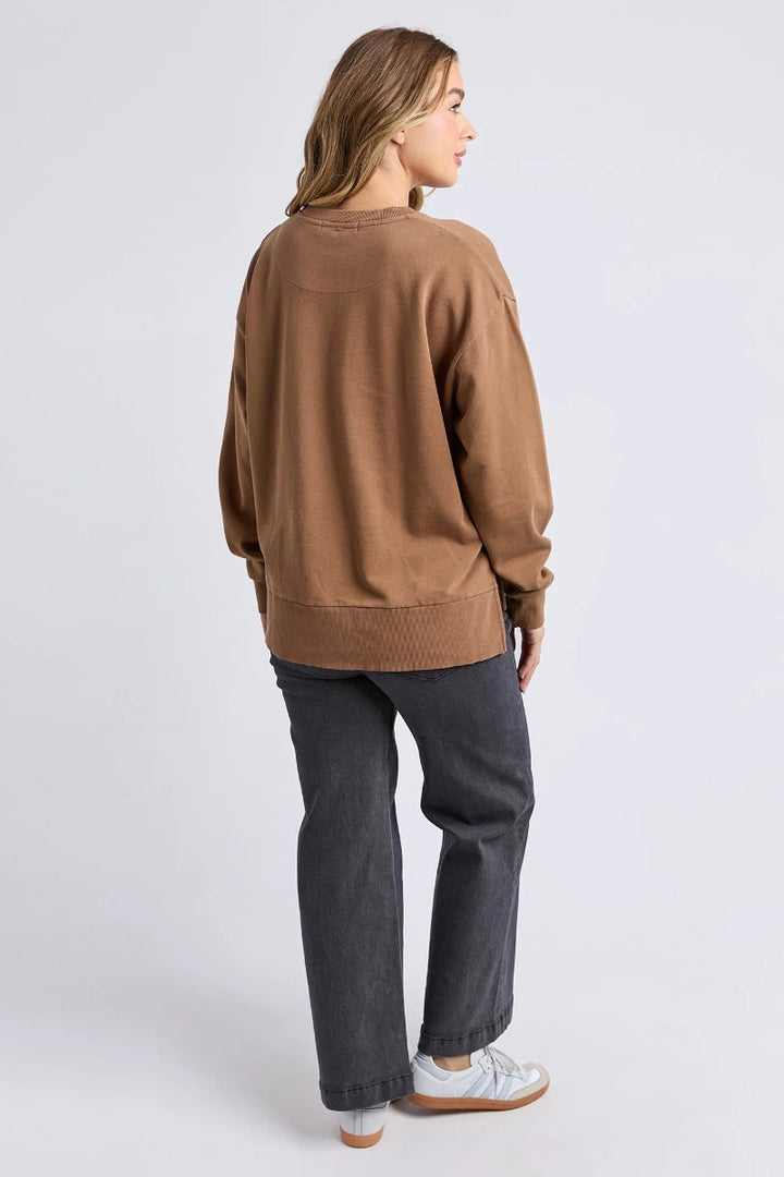 Person wearing a brown sweater and dark pants on a white background