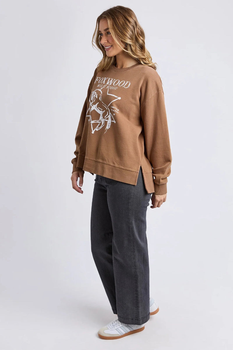 Woman wearing a brown sweatshirt with a logo and text, standing against a white background