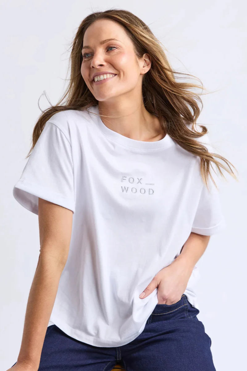 Woman wearing a white t-shirt with 'FOX WOOD' logo on a plain background