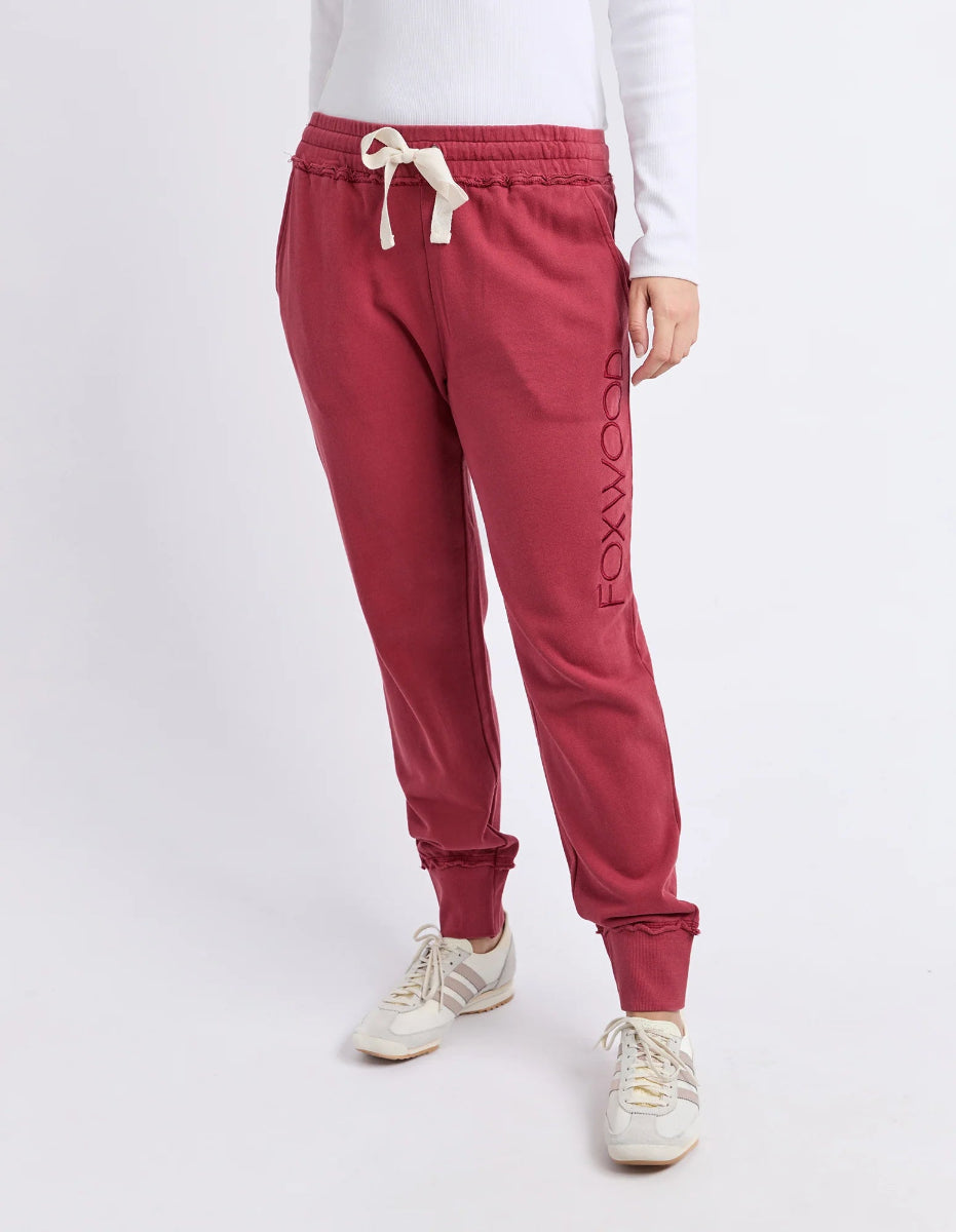 Full-length view of rust Foxwood track pants with cuffed ankles and logo detail.