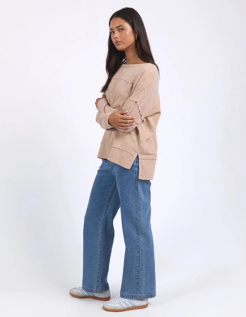 Woman wearing long sleeves Throw On Top in Oat color while standing in profile.