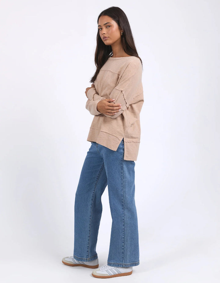 Woman wearing long sleeves Throw On Top in Oat color while standing in profile.