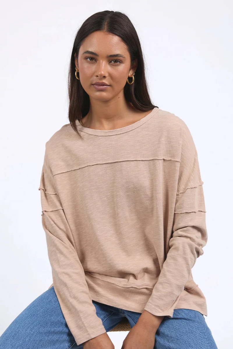 Woman wearing a beige sweater and blue jeans on a white background
