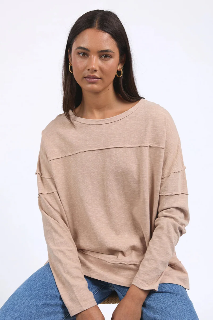 Woman wearing a beige sweater and blue jeans on a white background