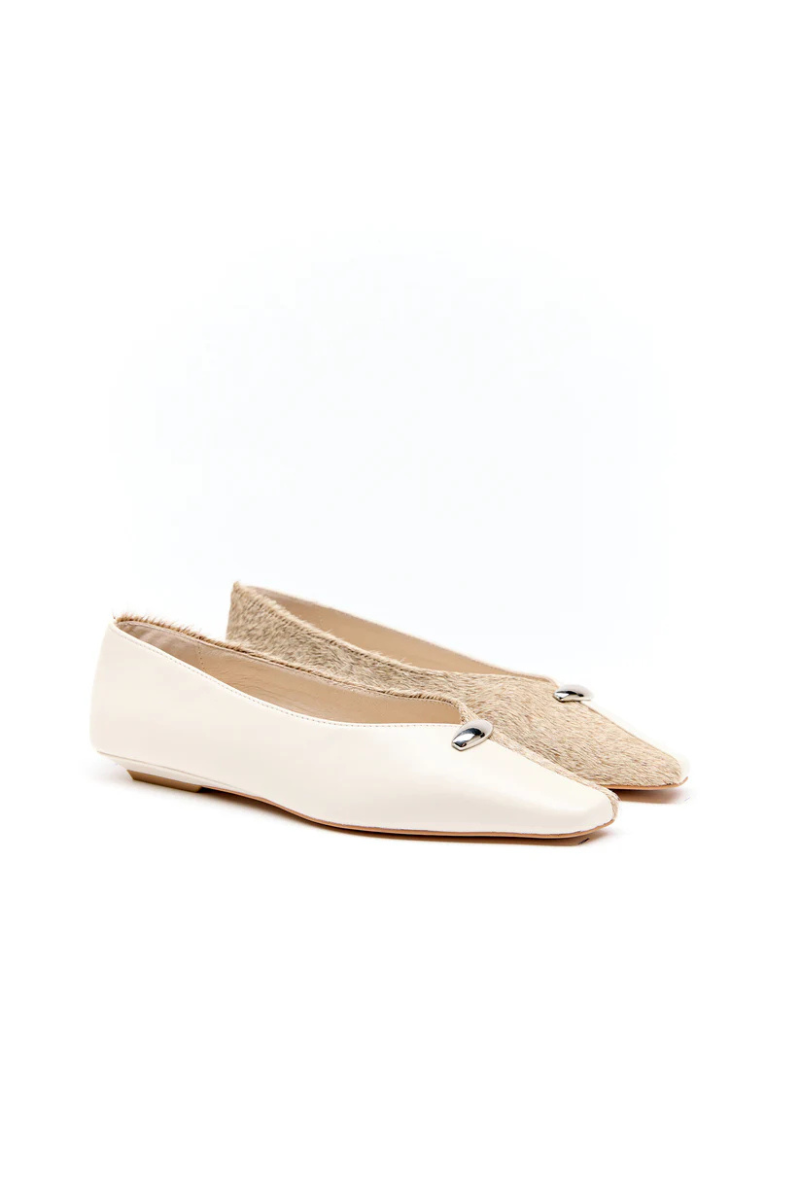 Pair of white flats with gold accents on a white background