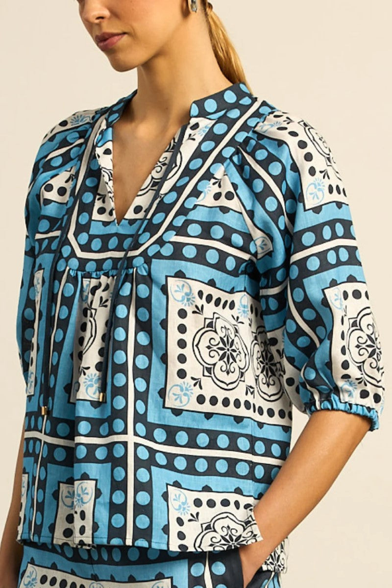 Woman wearing a blue patterned blouse with a beige background