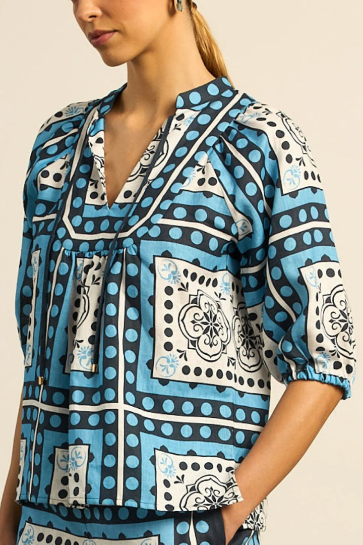 Woman wearing a blue patterned blouse with a beige background