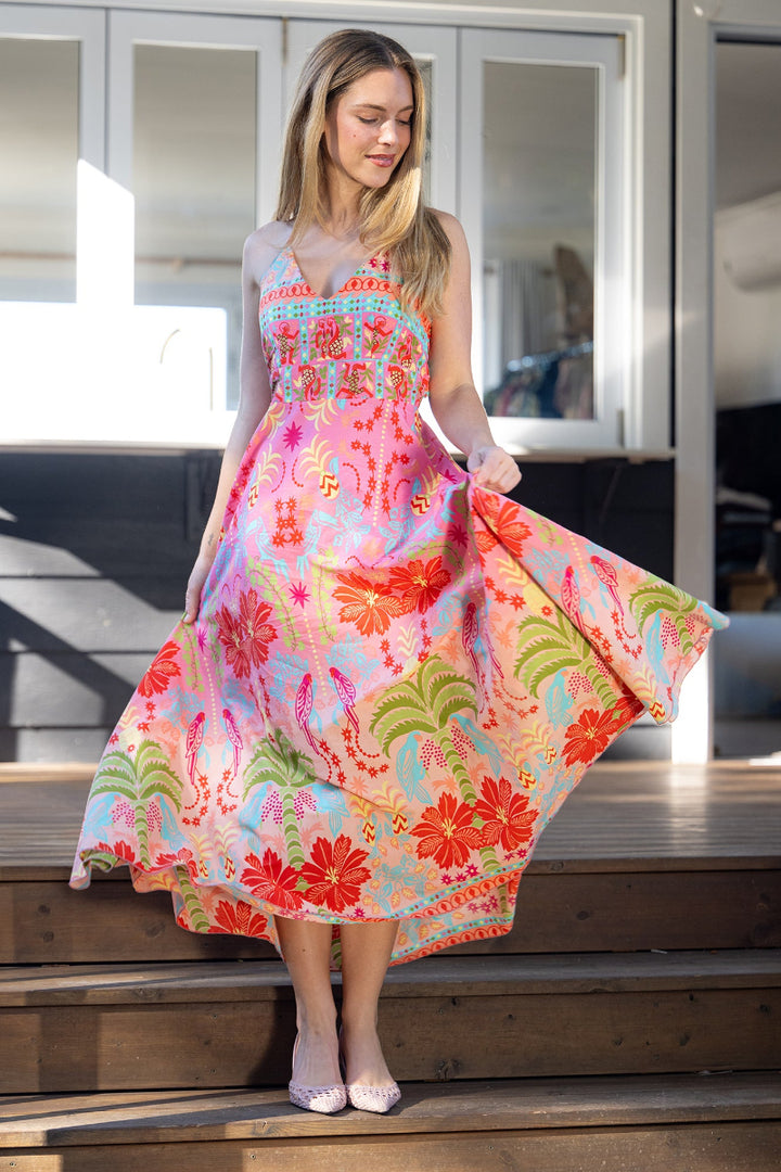 Woman wearing a colorful floral midi/maxi dress on wooden steps. The dress features a halter neck style and flowy skirt.