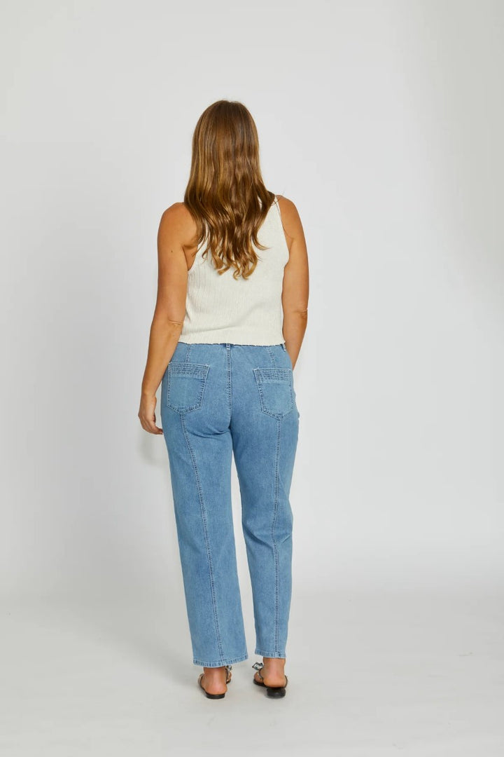 Woman wearing a white top and blue jeans on a plain background