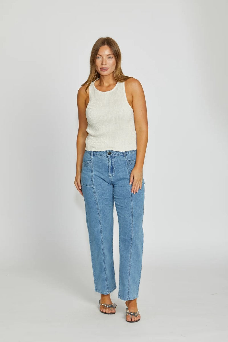 Woman wearing a white sleeveless top and blue jeans on a white background