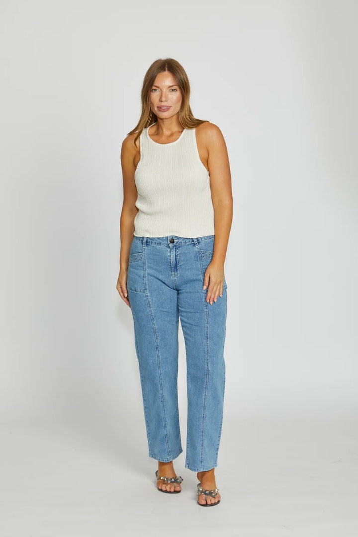 Woman wearing a white sleeveless top and blue jeans on a white background