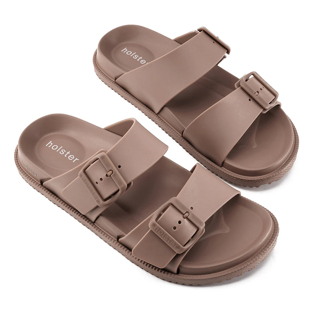 Pair of brown sandals with buckle straps on a white background