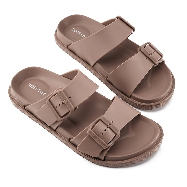 Pair of brown sandals with buckle straps on a white background