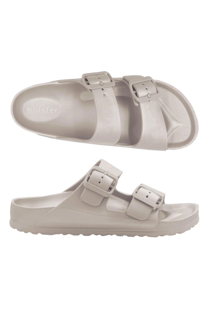 Pair of beige sandals with buckle straps on a white background