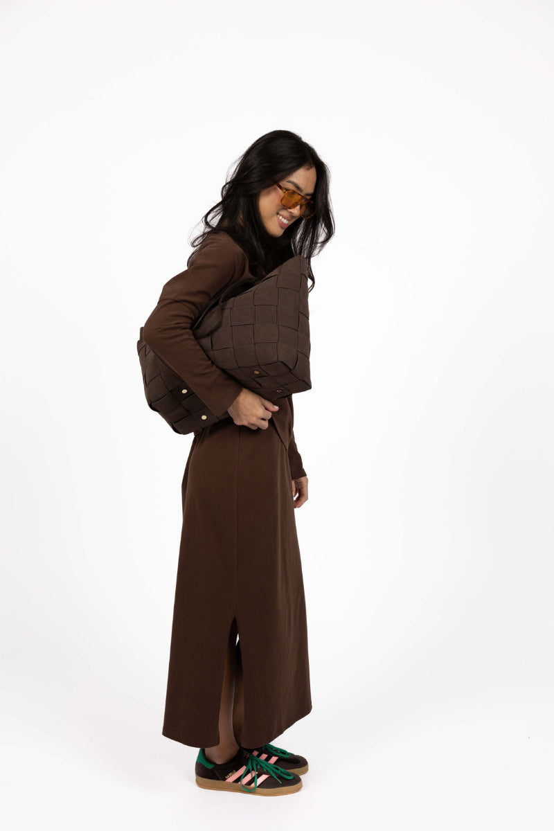 Woman wearing a brown outfit with a belt on a white background