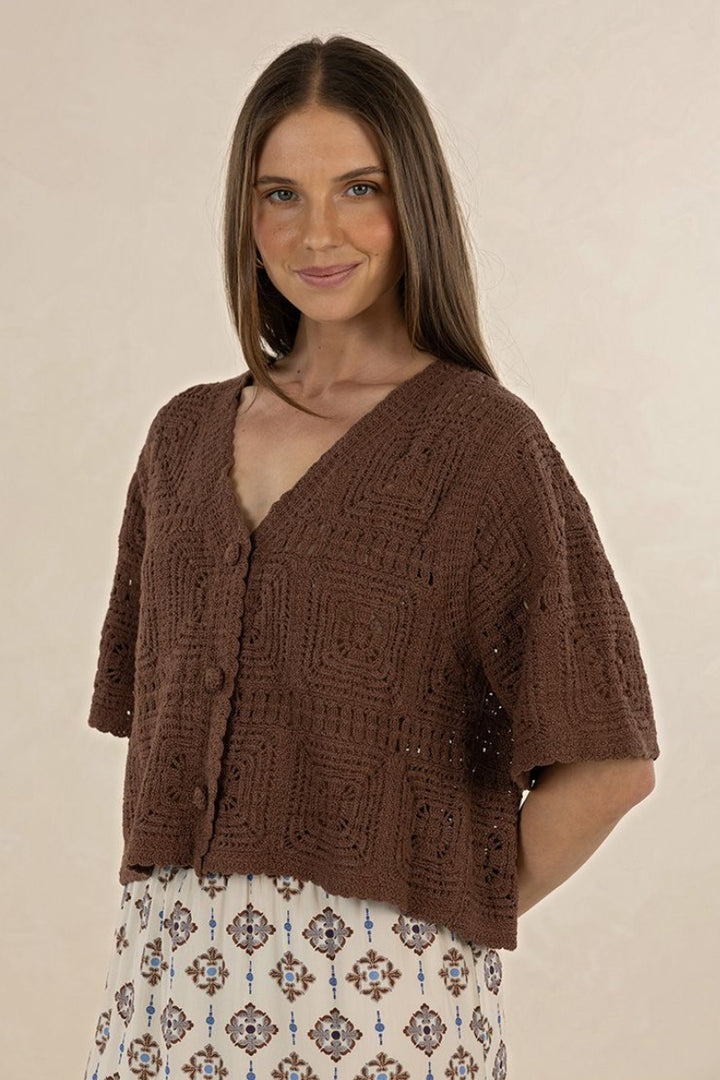 Woman wearing a brown knitted cardigan against a beige background