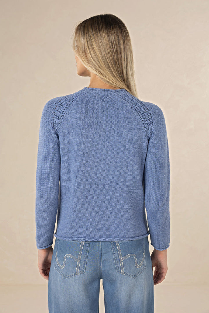 Woman wearing a blue sweater and jeans on a beige background