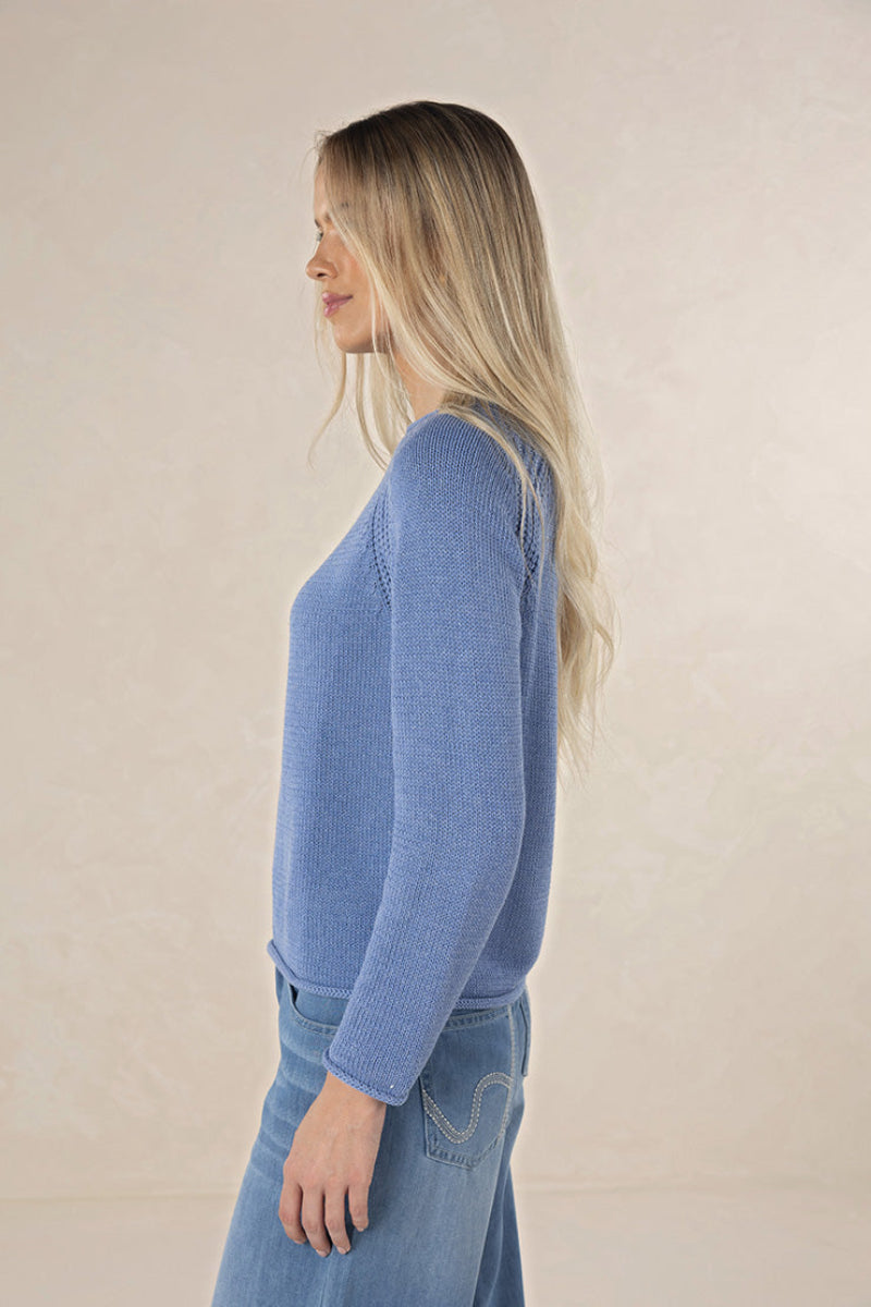 Woman wearing a blue sweater and jeans against a beige background