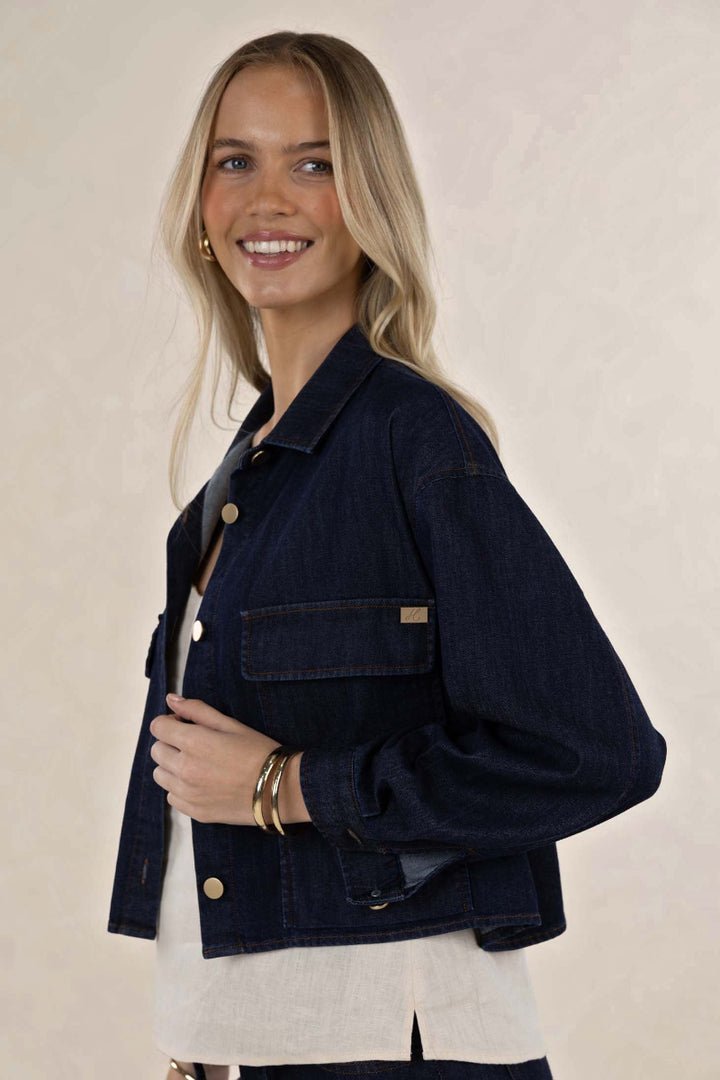 Woman wearing a dark denim jacket on a beige background