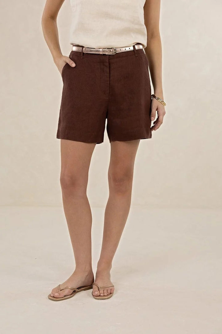 Person wearing brown shorts on a beige background