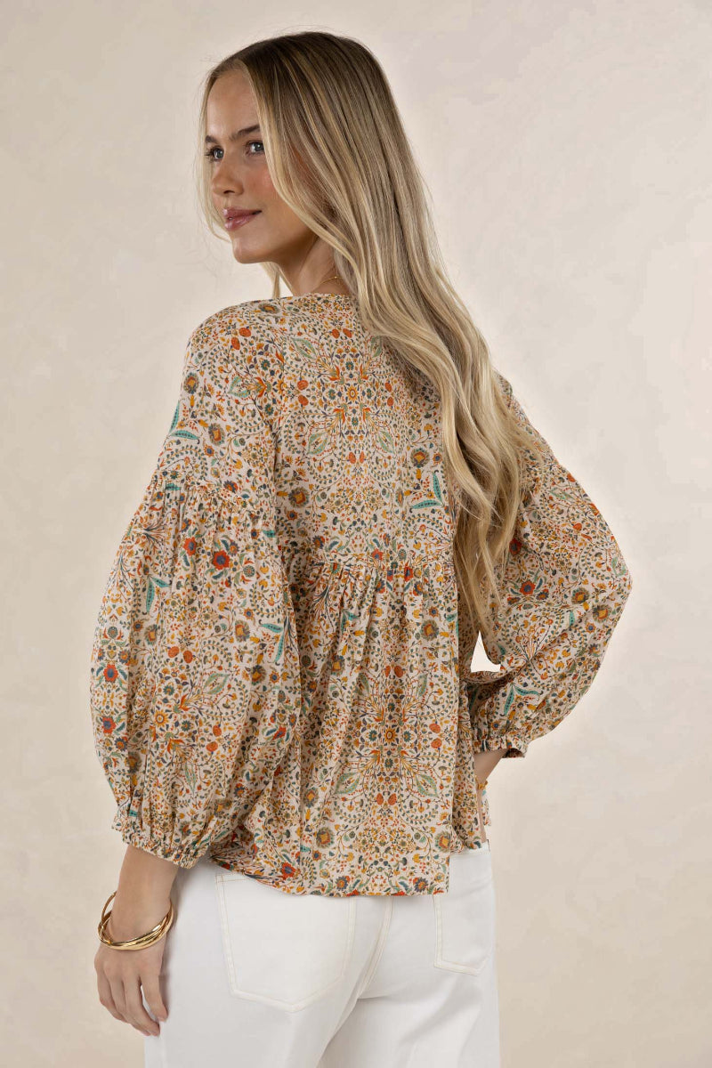 Woman wearing a floral blouse with long sleeves on a beige background