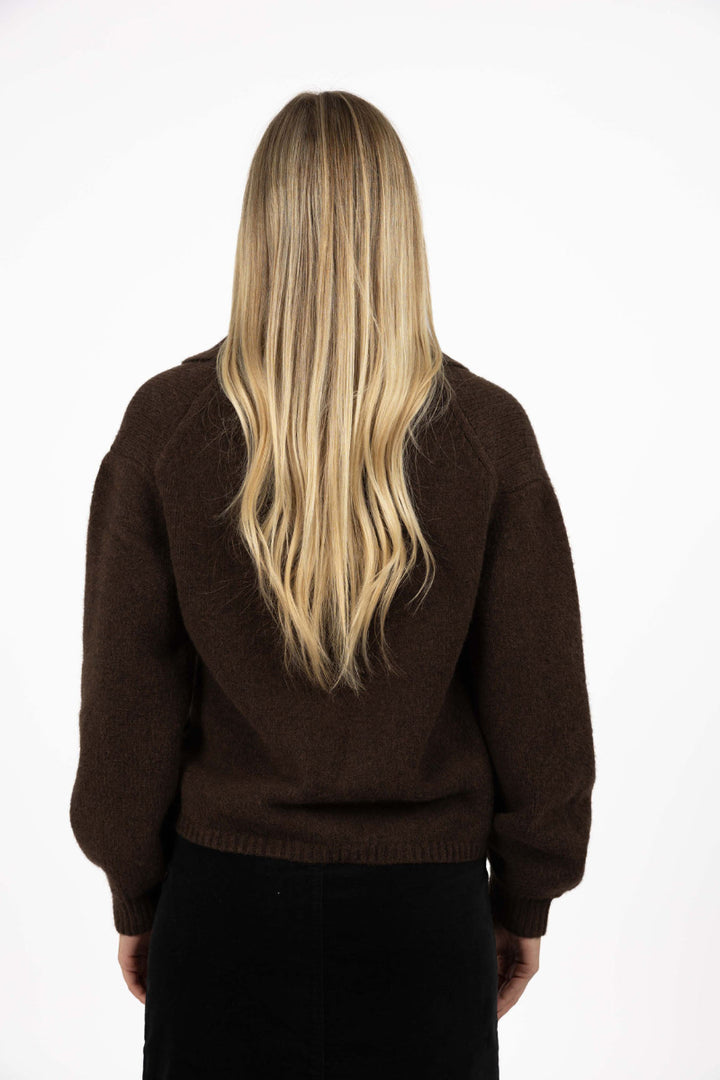 Person wearing a brown sweater with a plain white background