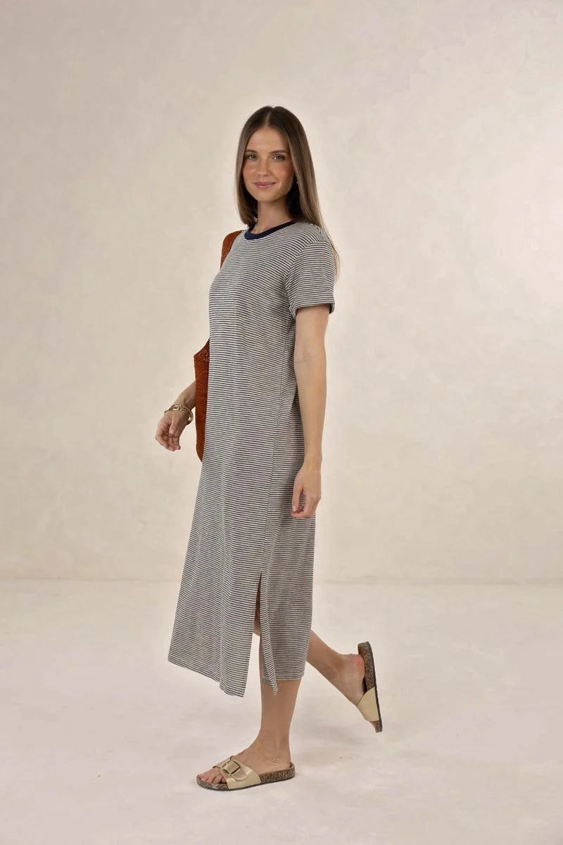 Woman wearing a gray dress with a black neckline against a plain background