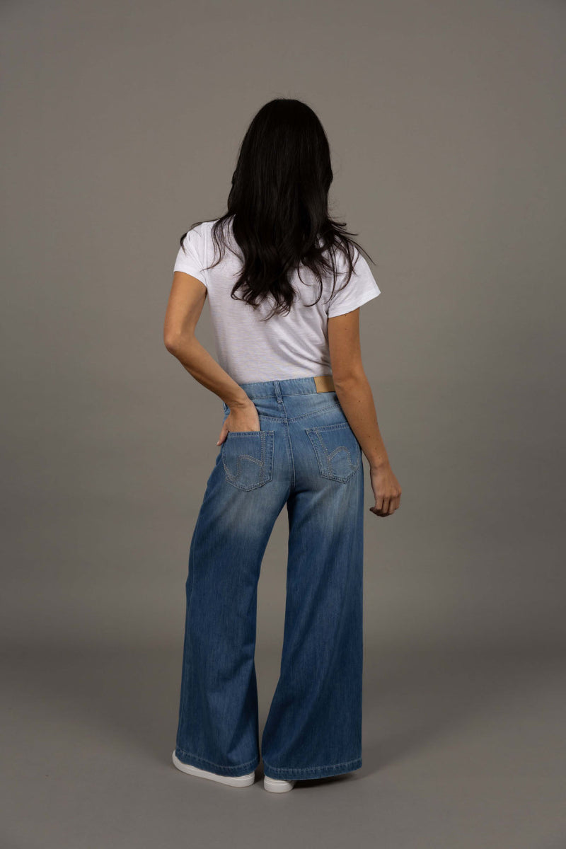 Person wearing a white t-shirt and blue jeans against a gray background