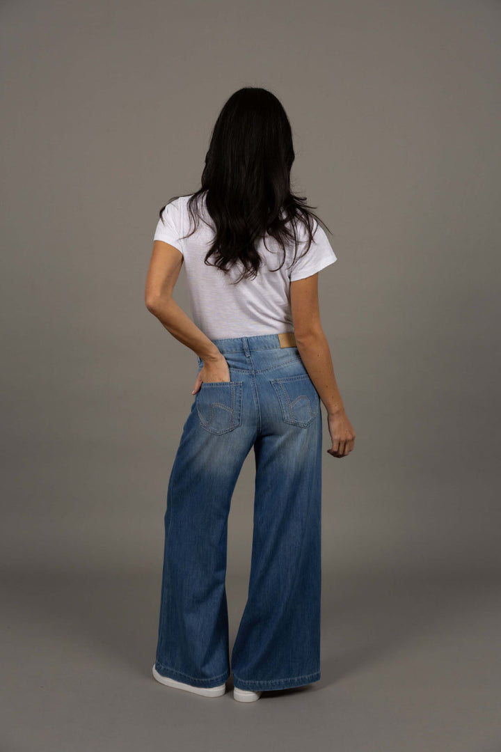 Person wearing a white t-shirt and blue jeans against a gray background