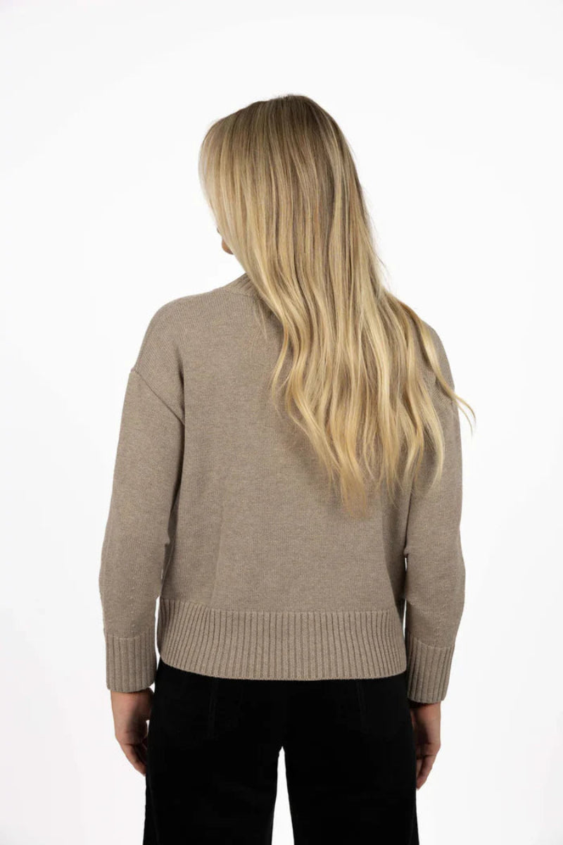 Person wearing a beige sweater on a white background