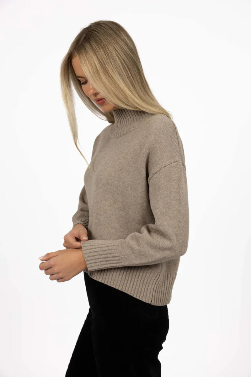 Woman wearing a beige sweater on a white background