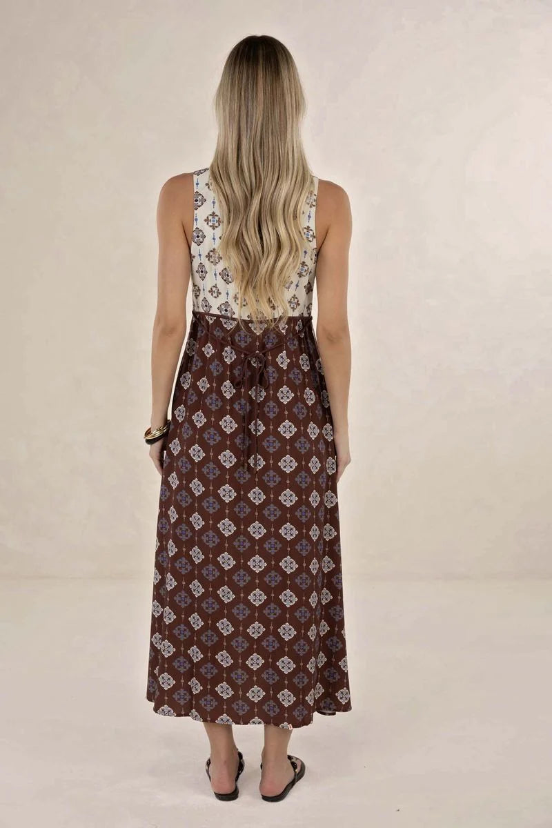Woman wearing a sleeveless top and patterned skirt on a beige background