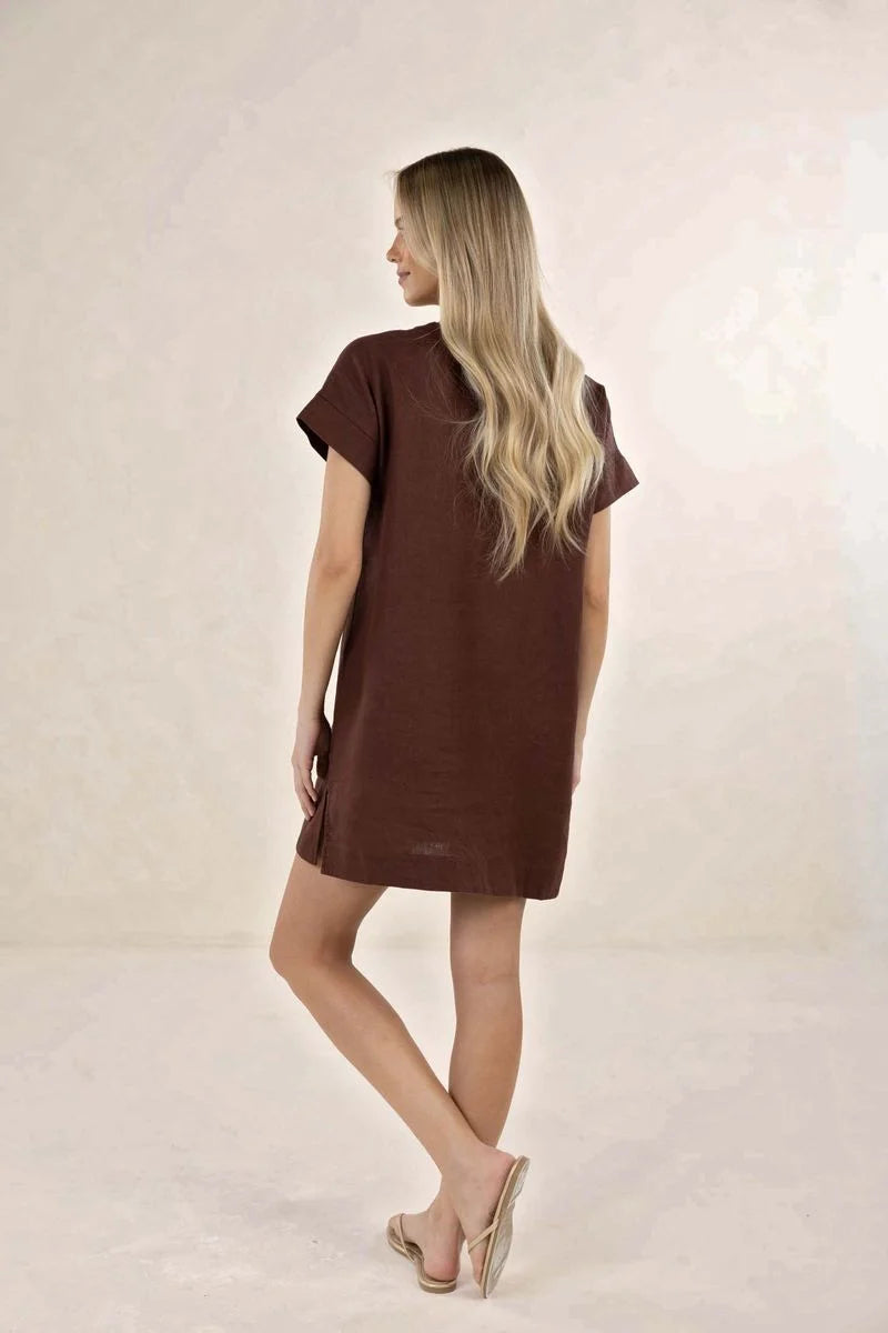 Woman wearing a brown dress against a plain background