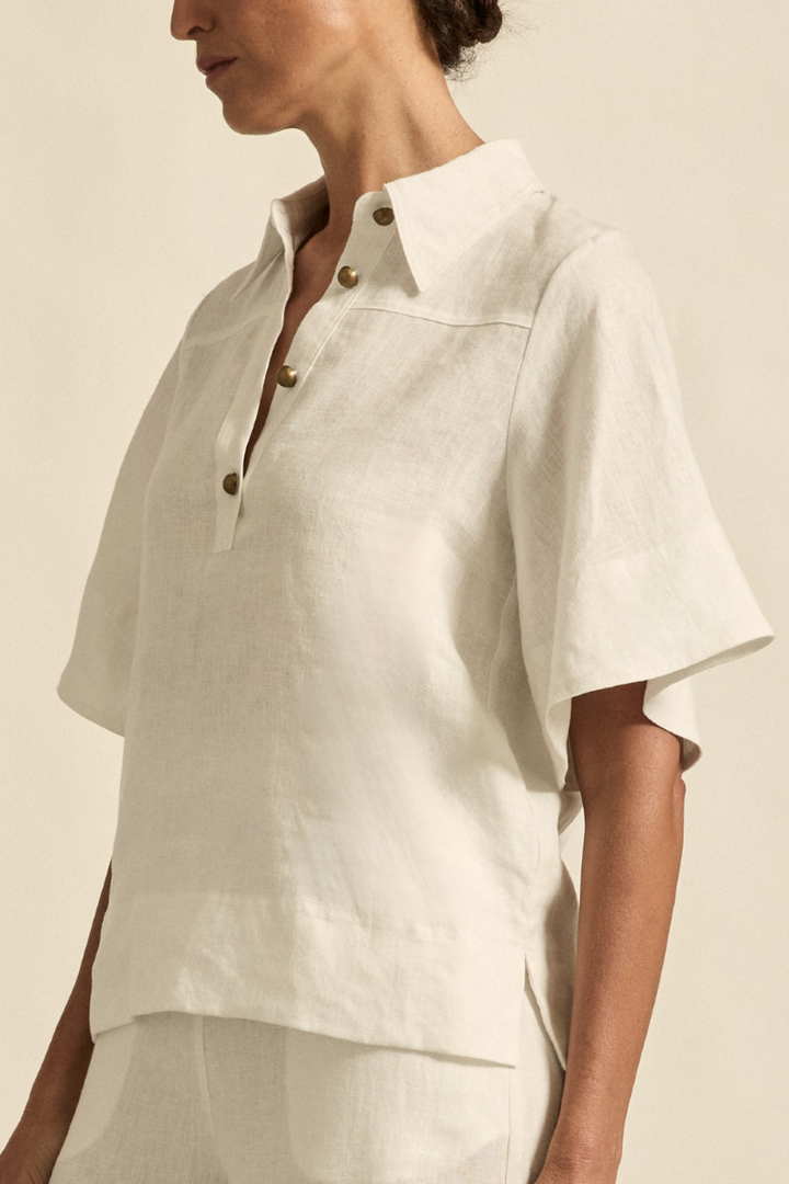 This side view of the Insinuate Top in Porcelain highlights the flutter sleeves, clean silhouette, and refined tailoring for a sophisticated, feminine look.
