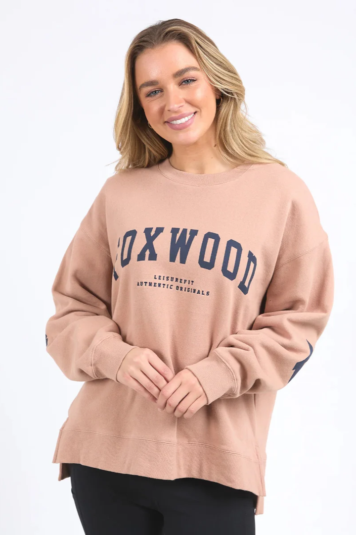 Women wearing a relaxed fit tan Foxwood interval crew sweatshirt in a neutral background.