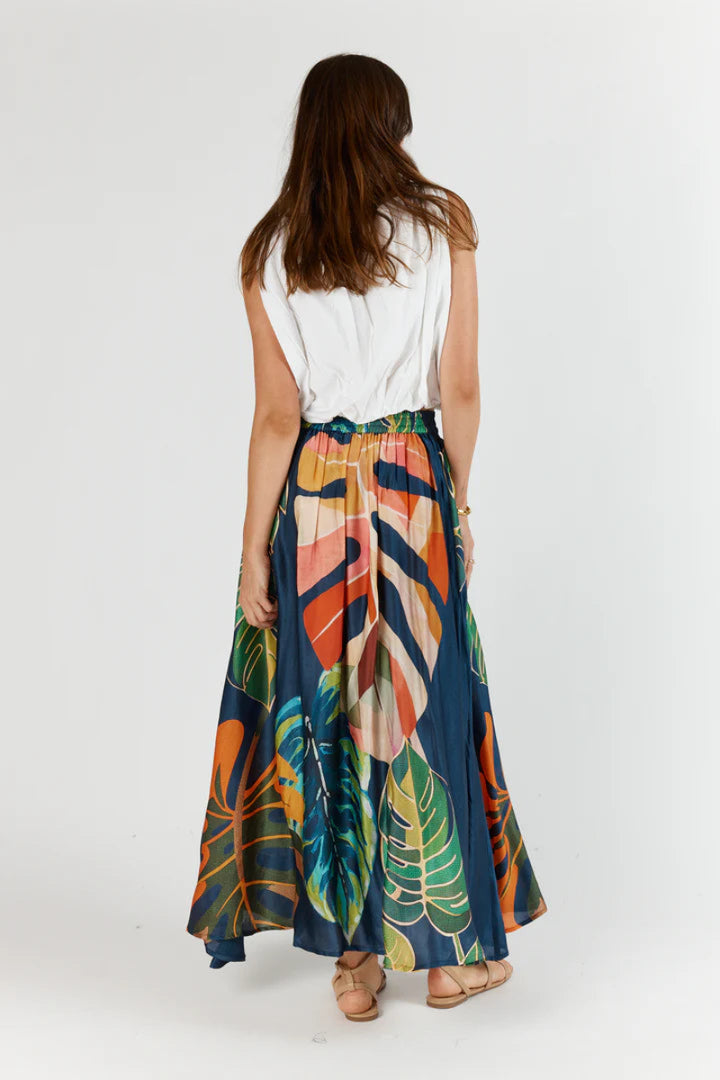 Woman wearing a colorful tropical leaf skirt on a white background