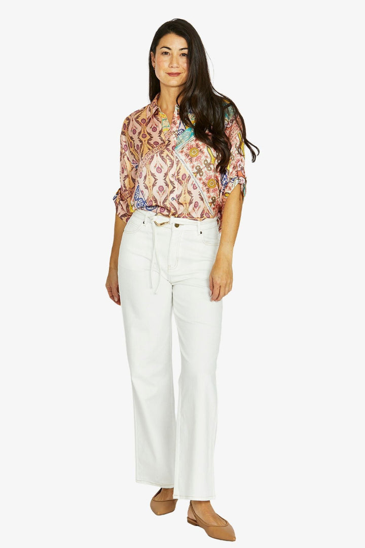 Woman wearing a floral blouse and white pants on a white background