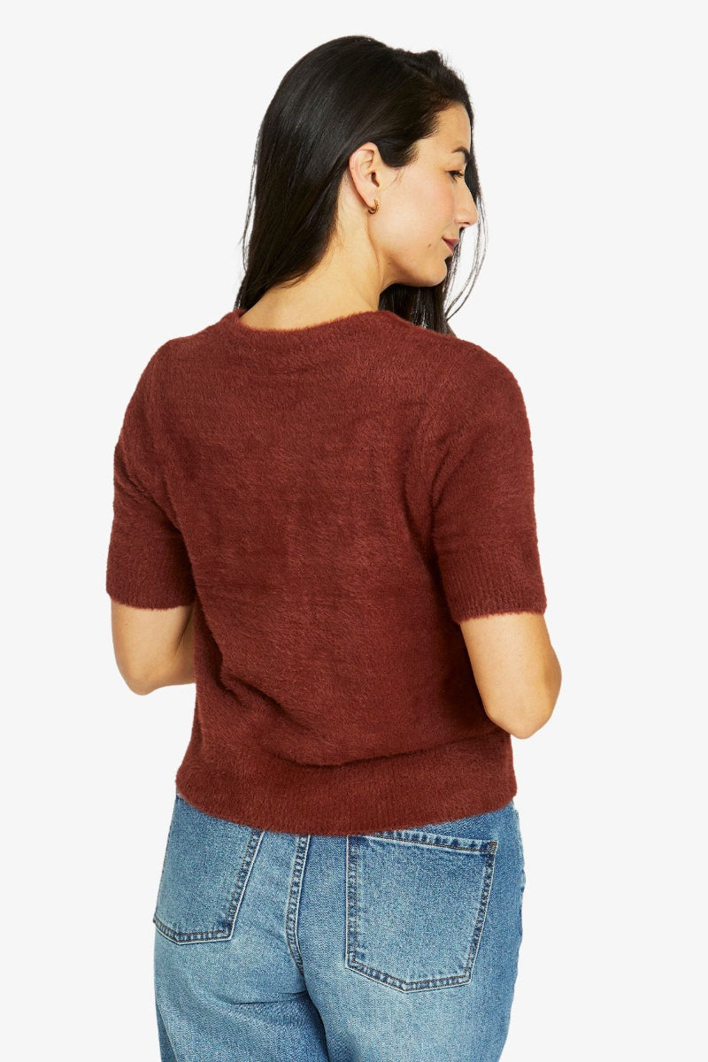 Woman wearing a brown sweater and blue jeans on a white background