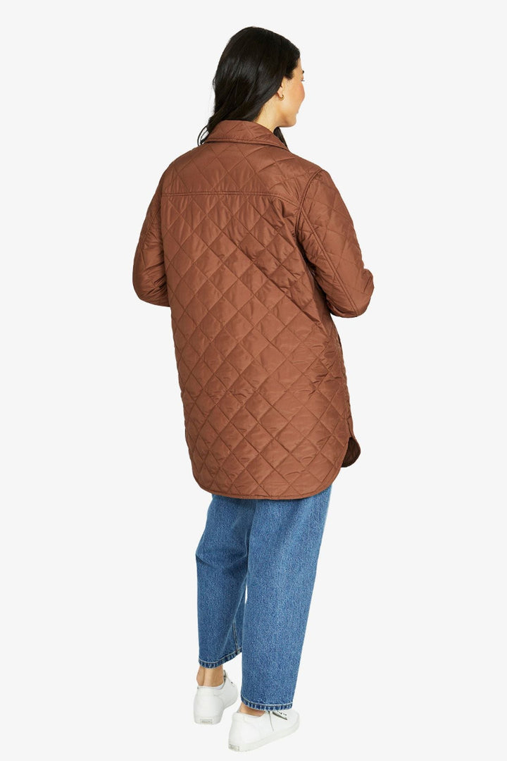 Person wearing a brown quilted jacket on a white background