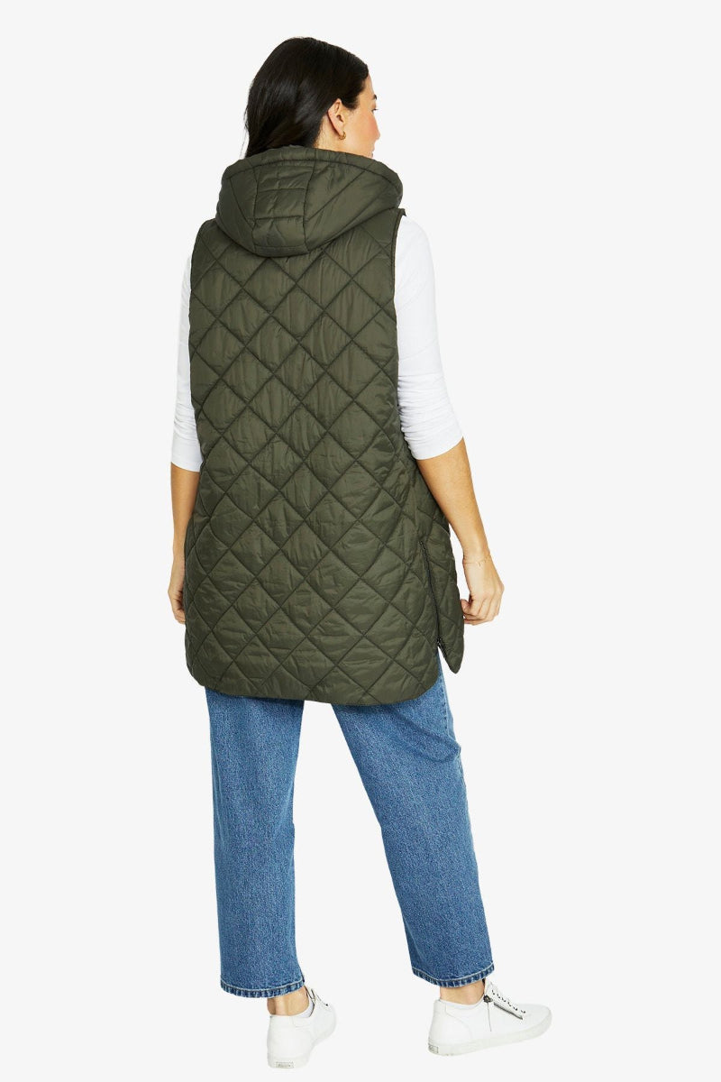 Person wearing a green quilted vest on a white background