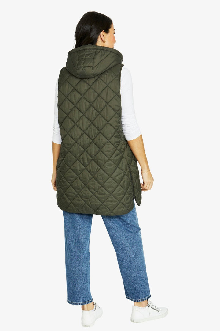 Person wearing a green quilted vest on a white background