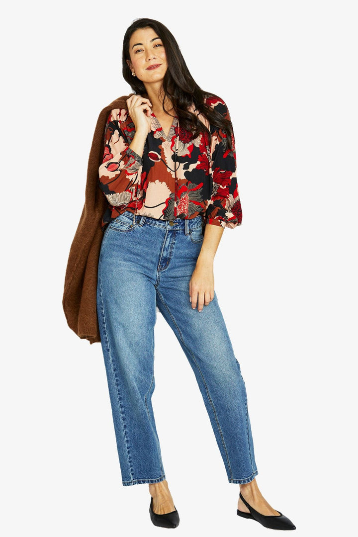 Woman wearing a floral blouse and blue jeans on a white background