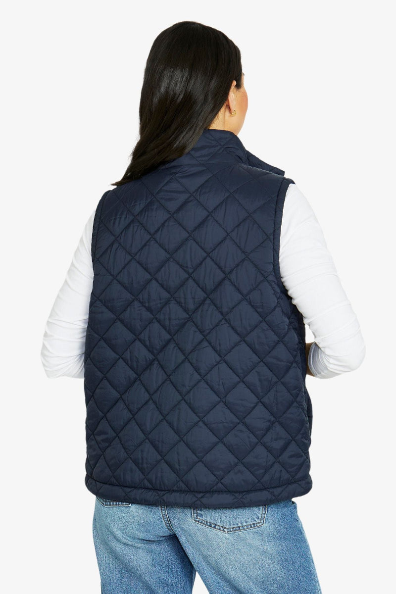 Person wearing a navy quilted vest on a white background